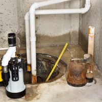 Replacing the old sump pump in a basement with a new one to drain the collected ground water from the sump or pit